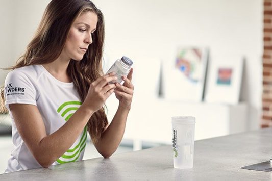 woman holding zinc tablets next to a shaker bottle