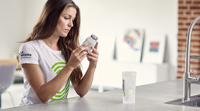 woman holding zinc tablets next to a shaker bottle